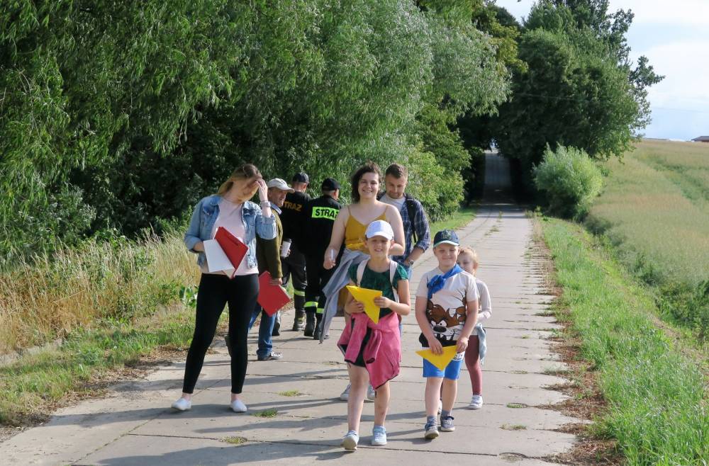 Okolice Kraczewa,drzewa, pola, pomiędzy asfaltowa droga, grupa uczestników gry terenowej , troje dzieci i trzech opiekunów 